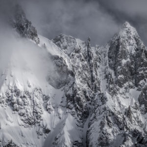 Photograph of the snow-covered Aiguille de Rochefort, surrounded by threatening clouds after a storm in the Mont Blanc massif.