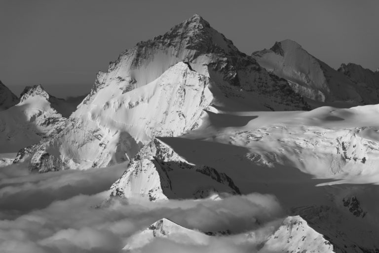 black and white photo of Dent Blanche - Grand Cornier and Dent d&#039;Hérens in a sea of clouds