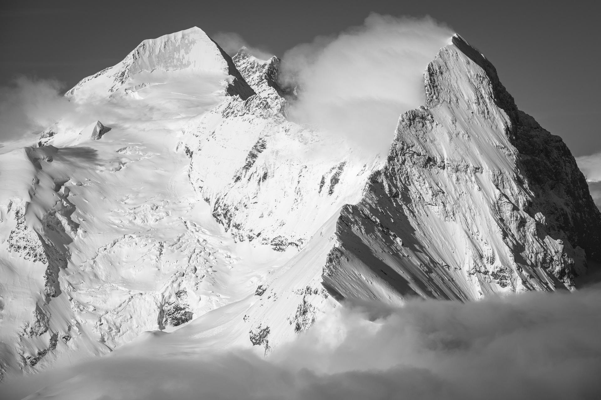 Monch - Eiger - Jungfrau - Wolkenmeer auf dem Gipfel eines Berges in den Schweizer Alpen in schwarz-weiß - grindelwald