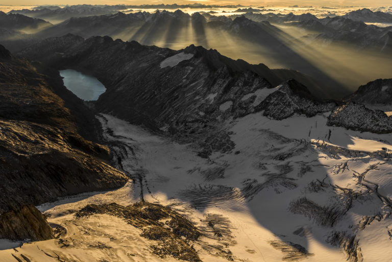 Panorama de montagne dans les Alpes Bernoises en Suisse - Vue aérienne en lever de soleil sur les montagnes rocheuses enneigées et d'un lac en montagne - Oberaar