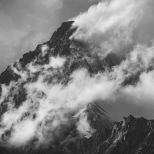 Black and white picture of a sea of clouds on a smoking mountain top -  Obergabelhorn in the Alps of Zermatt in Switzerland