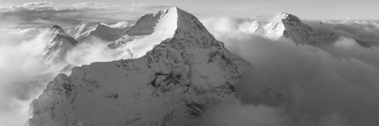 Schwarz-Weiß-Panoramafoto auf dem Monch und der Jungfrau. Foto der Gipfel von Grindelwald , die nach einem Sturm aus dem Wolkenmeer auftauchen.