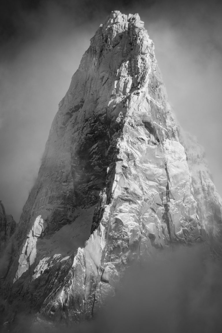 Schwarz-Weiß-Foto von Les Drus Chamonix - Gipfel von Les Drus nach einem Schneesturm, der aus dem Wolkenmeer kommt