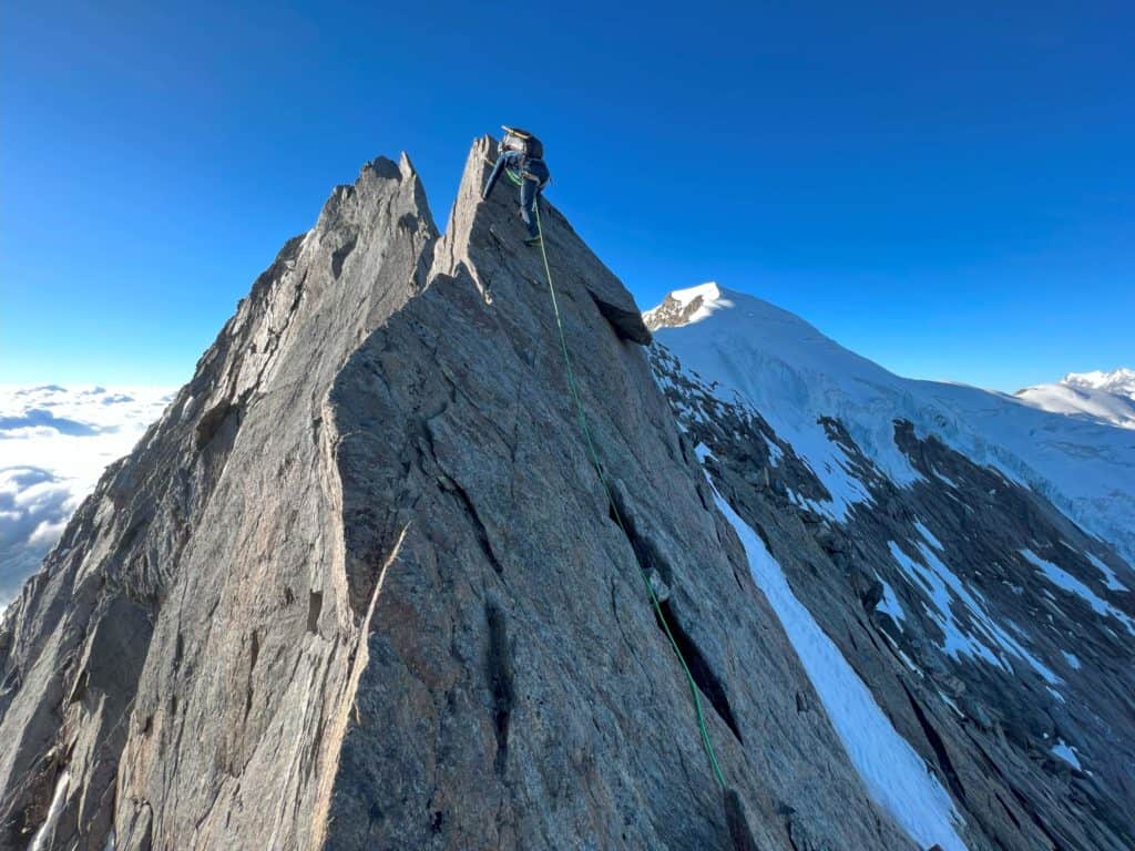 Alpiniste sur l'arête nord, le dôme du Weissmies apparaît en arrière plan