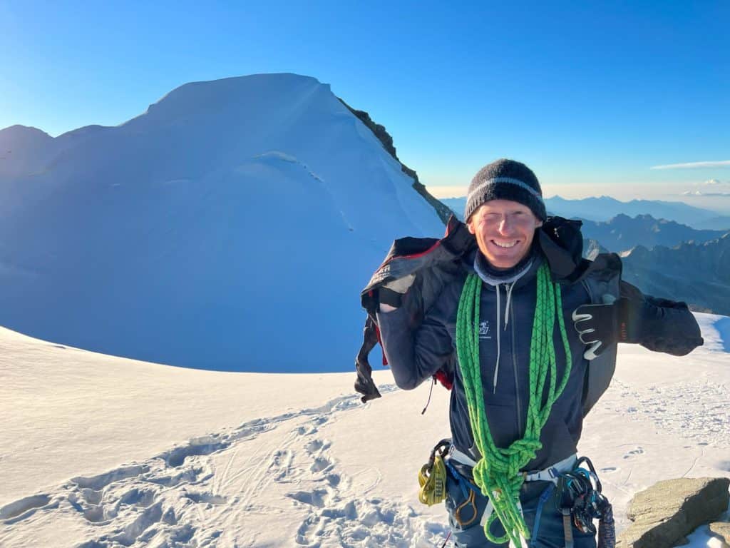 Guide de haute montagne très souriant devant le sommet du Combin de Valsorey