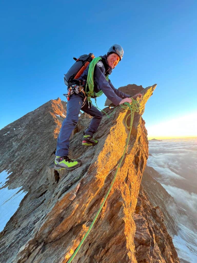 Guide de haute montagne, heureux, posant sur l’arête nord du Weissmies lever du soleil