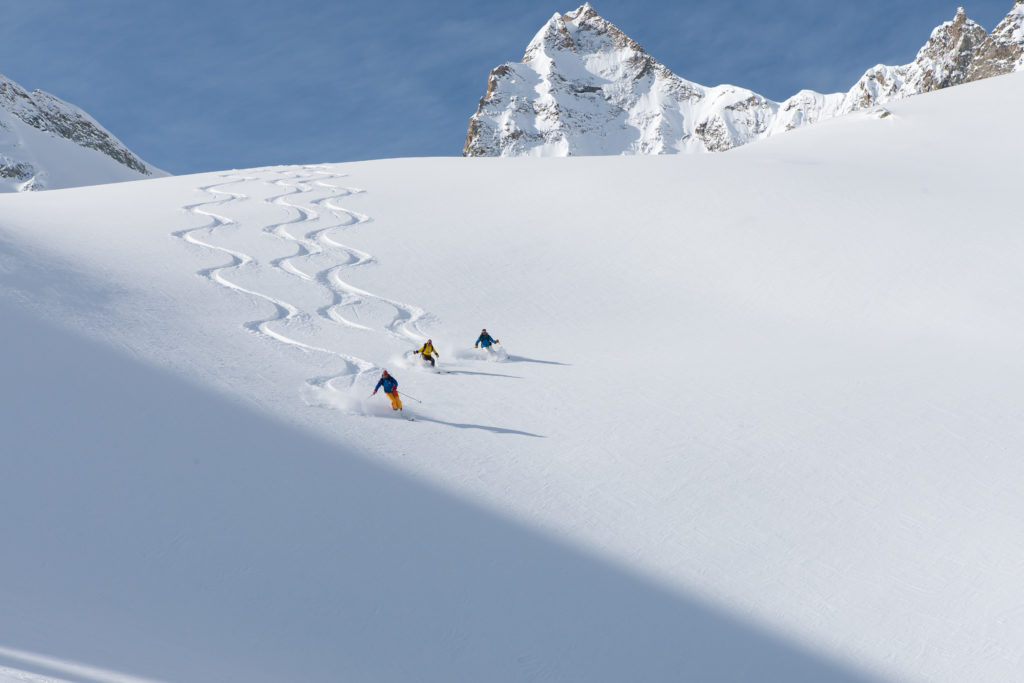 Trois skieurs descendant un champ de poudreuse