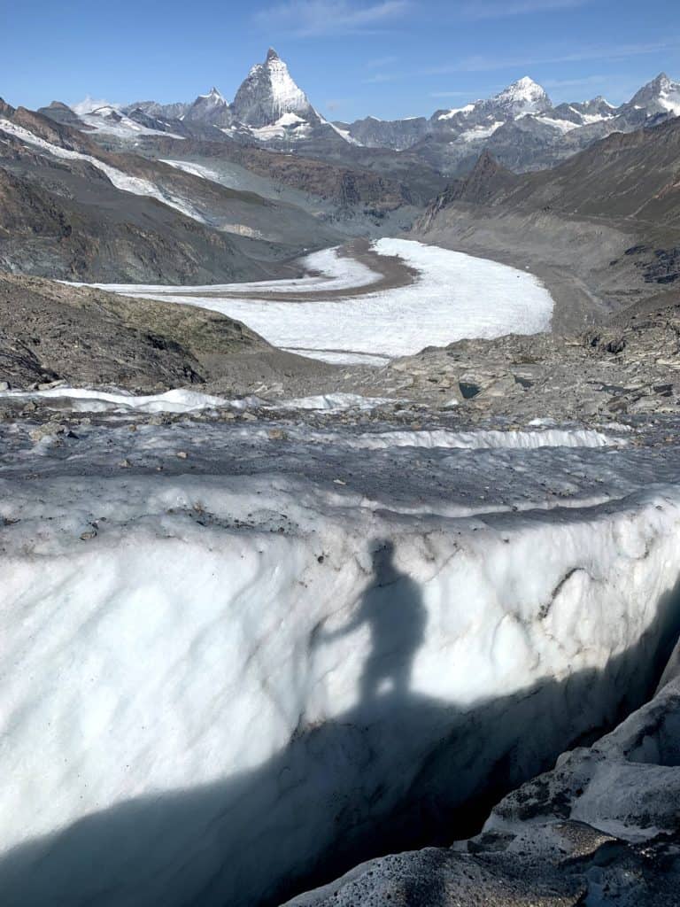 Ombre d'un alpiniste qui se reflète sur la crevasse du glacier gornergletscher. En arriève plan, le Cervin.