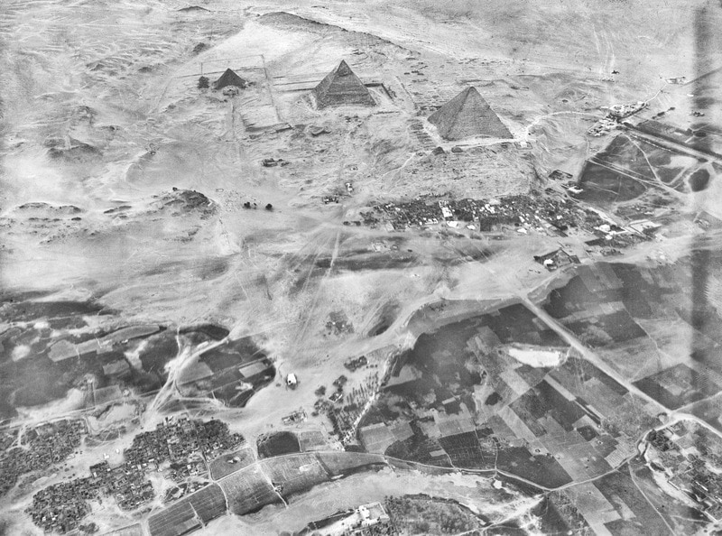 Photographie aérienne en noir et blanc des pyramides égyptiennes et des alentours.