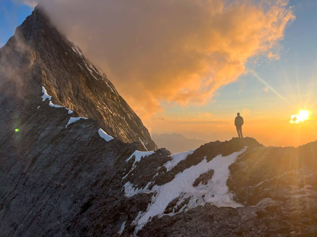 Man at foot of Mittellegi ridge with sunset behind him