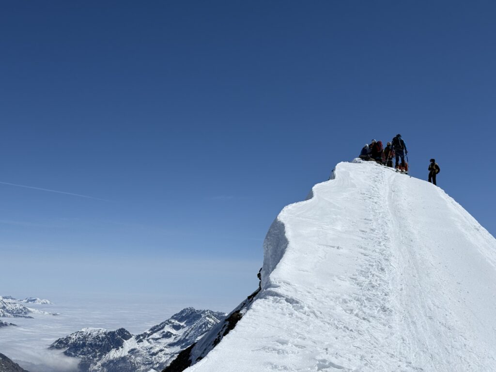 Gruppe von Bergsteigern auf einem verschneiten Gipfelgrat in den Alpen, fotografiert von Blaise Agresti
