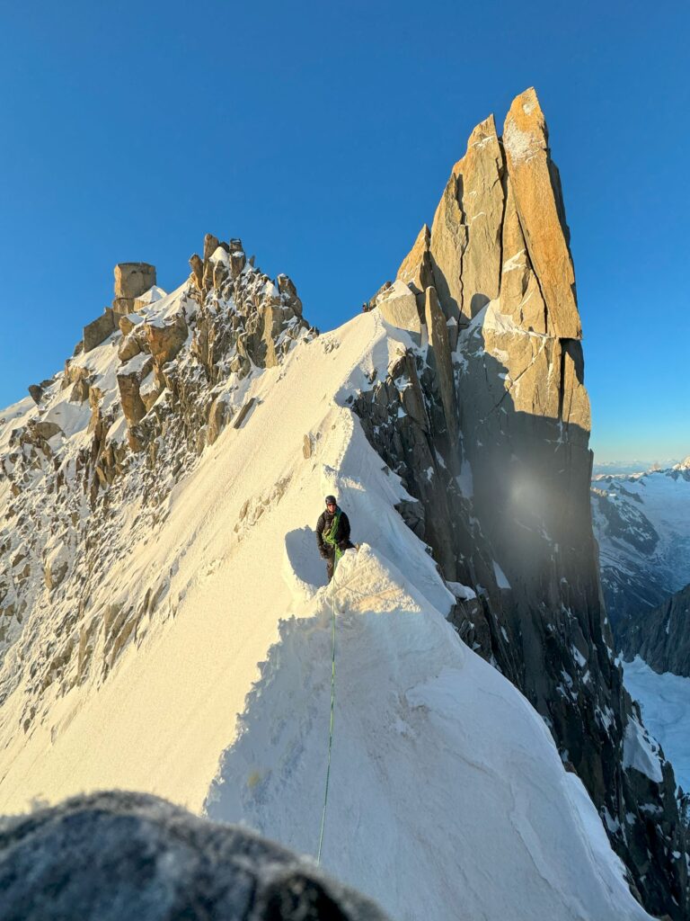 Mountaineer on the snow-covered ridge near the Aiguille Verte, Mont Blanc Massif.