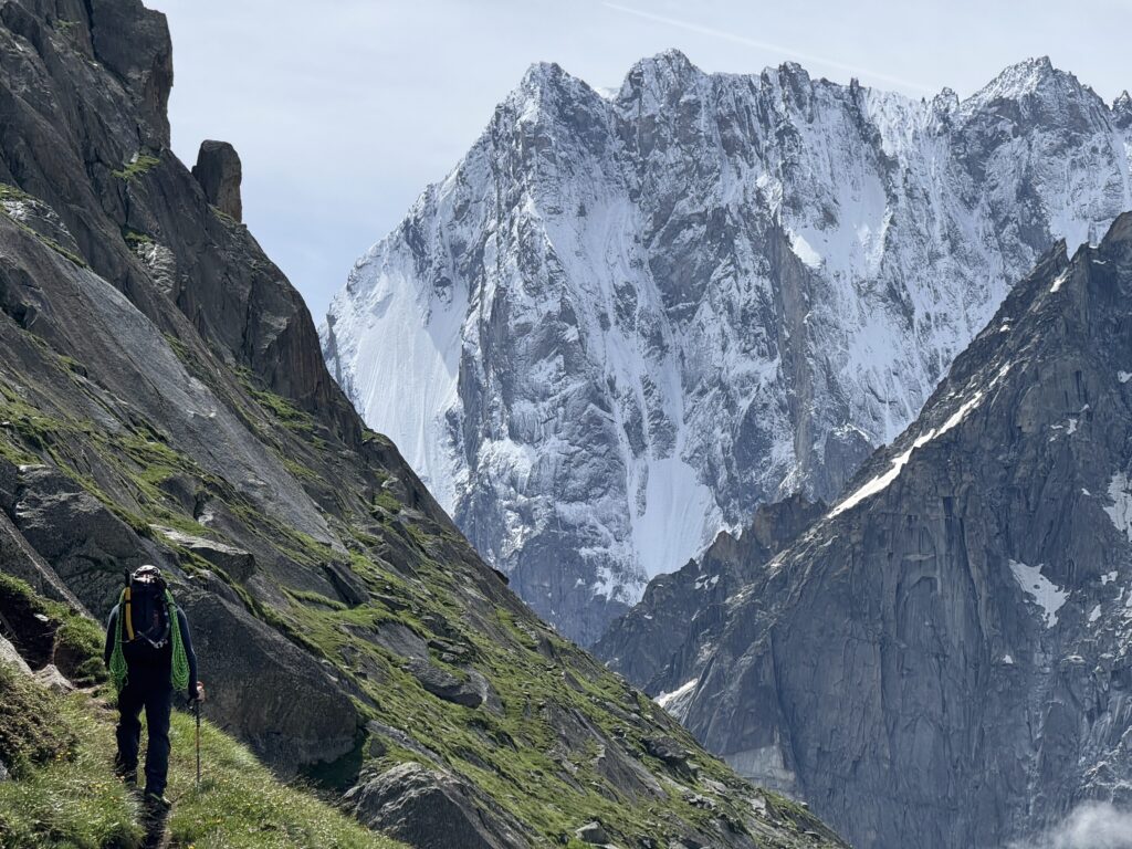 Mountaineer walking towards the former Couvercle refuge, with a view of the Grandes Jorasses in the background.
