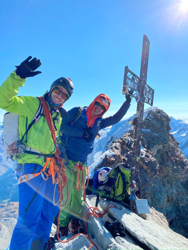Deux alpinistes heureux au sommet du Cervin au-dessus de Zermatt avec la croix métallique derrière eux