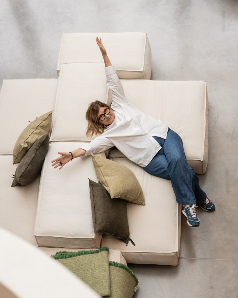 Innenarchitektin in einem Sofa, streckt die Arme aus, lächelt