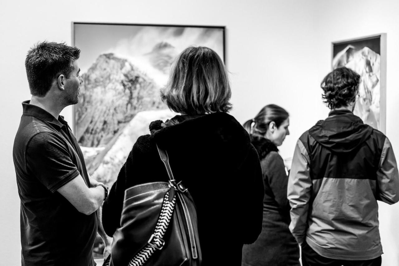 Personen, die fotografische Werke in einer Ausstellung in den Alpen betrachten