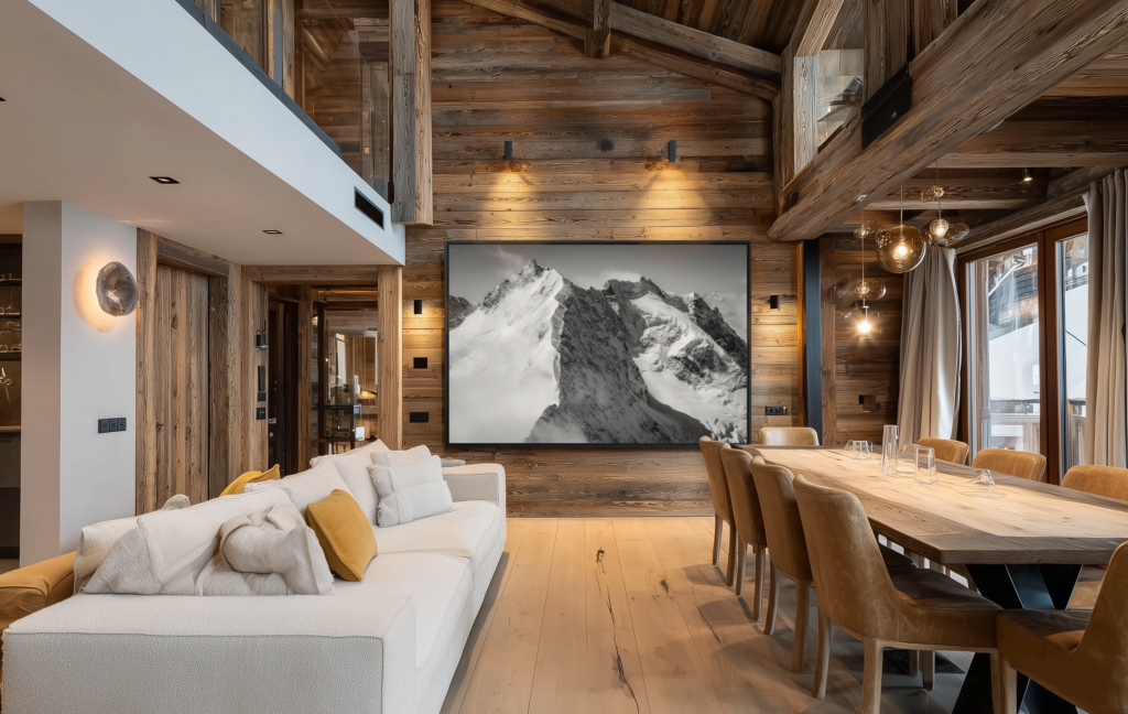 L’association du bois brut, du mobilier contemporain et d’une photographie de montagne en noir et blanc confère à ce chalet une atmosphère élégante, où authenticité alpine et raffinement moderne s’unissent avec harmonie.